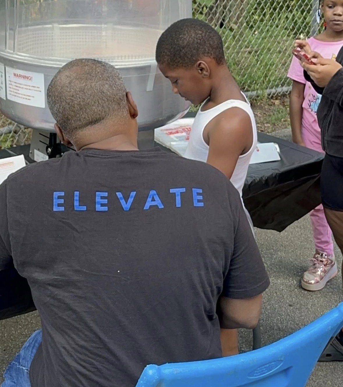 Marcel McDaniel seated with a child at a table during a Ceasefire community event.